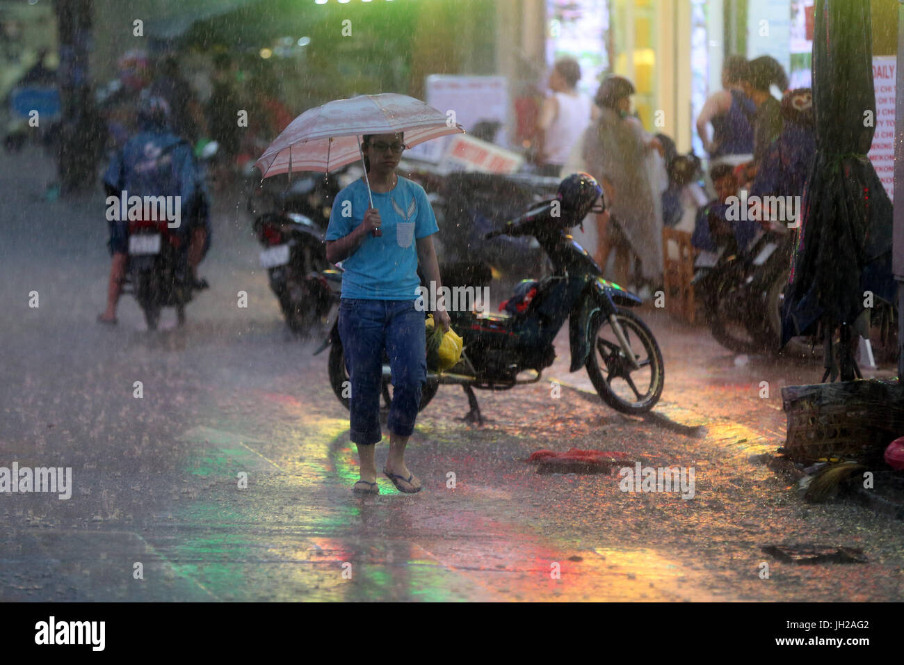 Schweren Monsunregen. Frau mit Regenschirm auf Saigon Street. Vietnam. Stockfoto