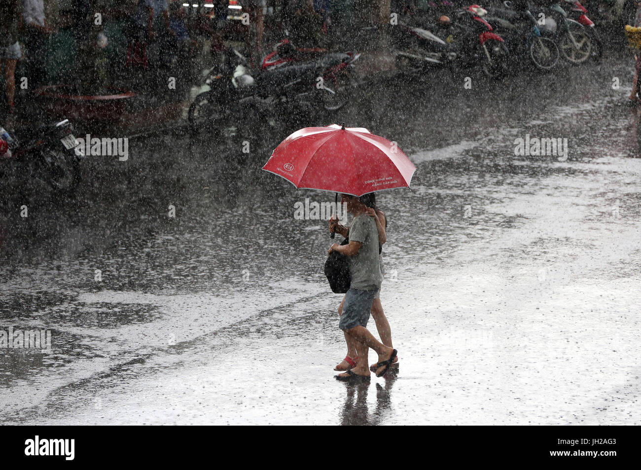 Schweren Monsunregen. Paar mit Regenschirm auf Saigon Street. Vietnam. Stockfoto