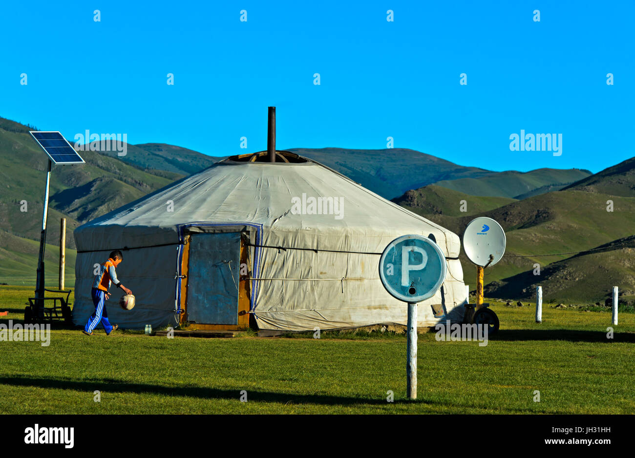 Junge spielt mit einem Ball an eine moderne Jurte mit Solarpanel, Sat-Schüssel und Parkplatz, Orkhon-Tal, Mongolei Stockfoto