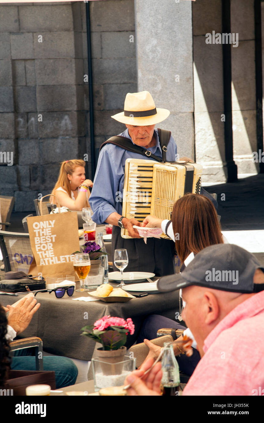 Mann in einem Strohhut Piano Akkordeon zu spielen, zu Essen in einem Restaurant auf der Piazza-Bürgermeister / Plaza Mayor Madrid Stockfoto