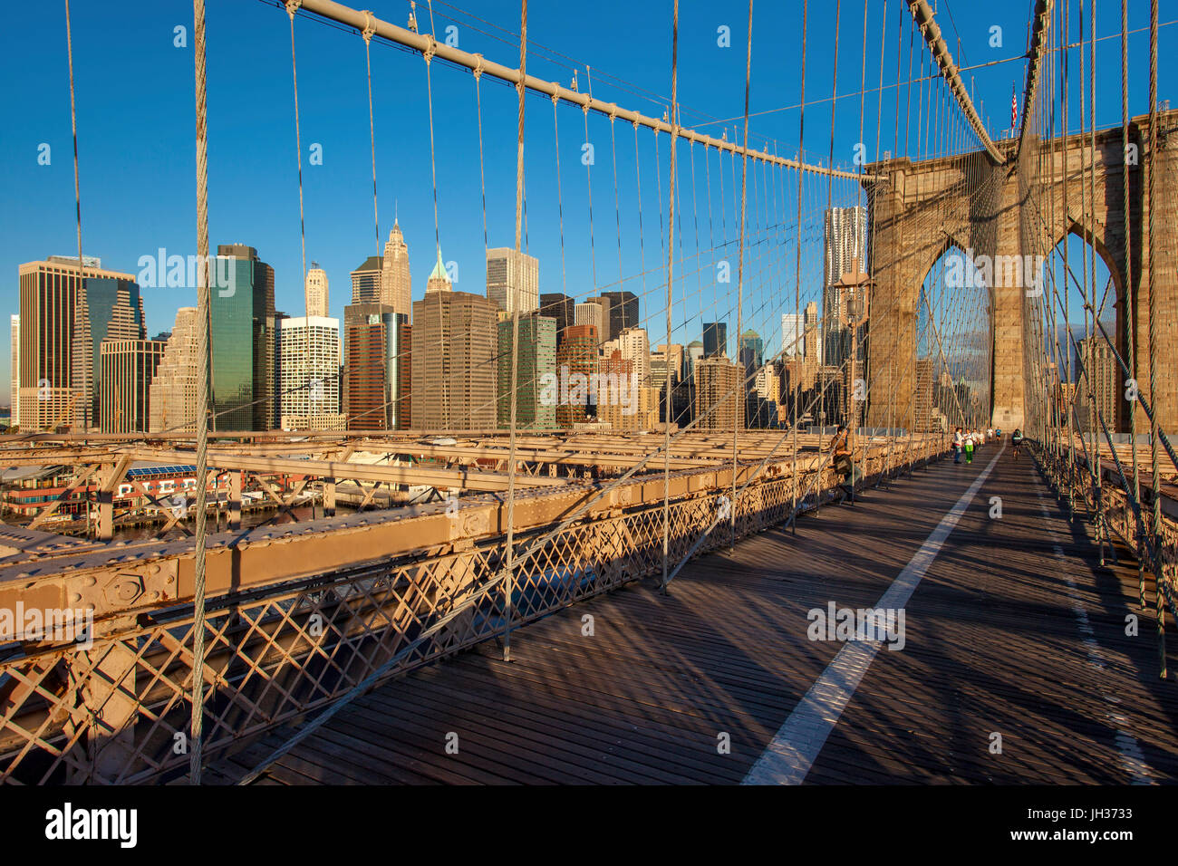 Am frühen Morgen auf der Brooklyn Bridge mit den Gebäuden von lower Manhattan über New York City, USA Stockfoto
