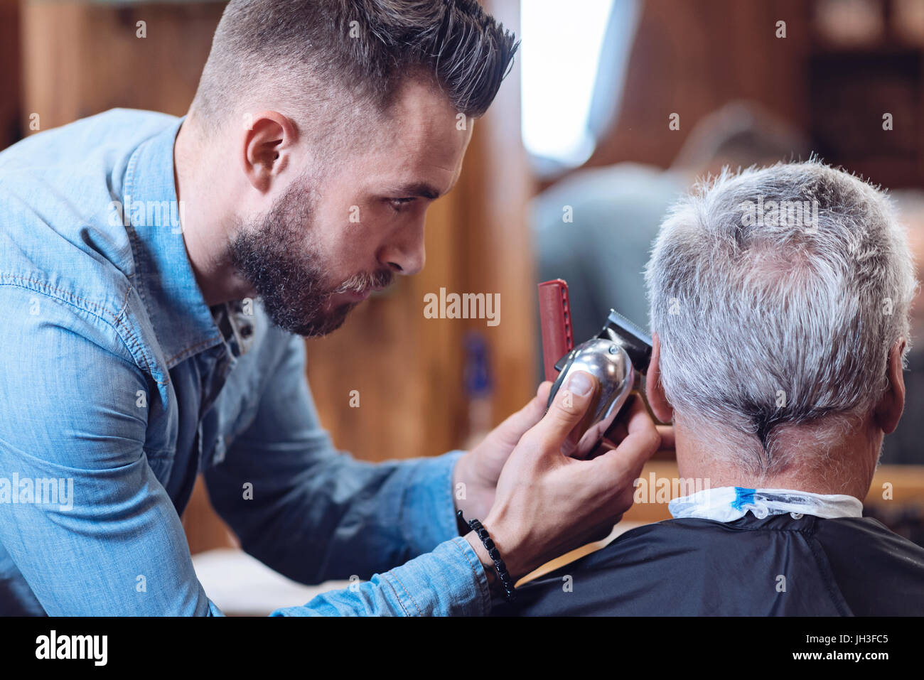 Professionelle männliche Friseur hält eine Haarschneidemaschine Stockfoto