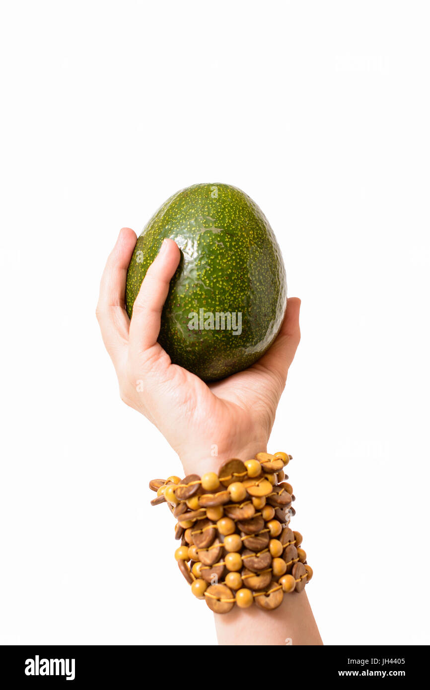 Avocado mit einem Armband um ihr Handgelenk gewickelt von einer weiblichen Hand gehalten Stockfoto