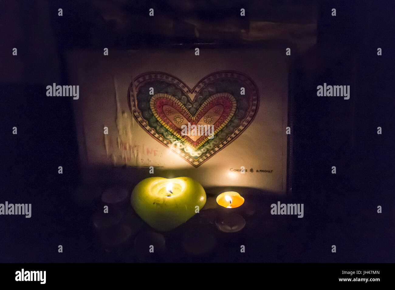 Herzförmige Kerze glimmering einen farbigen Herzen Zeichnung. Spontane Hommage an die Opfer der Terroranschläge in Paris, den 13. November 2015: Stockfoto