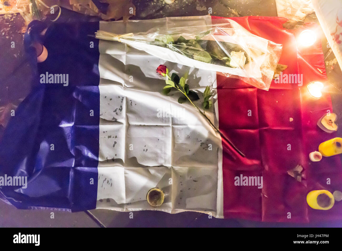 Französisch blau weiß-rote Flagge mit Rosen und Kerzen. Spontane Hommage an die Opfer der Terroranschläge in Paris 13. November 2015. Stockfoto