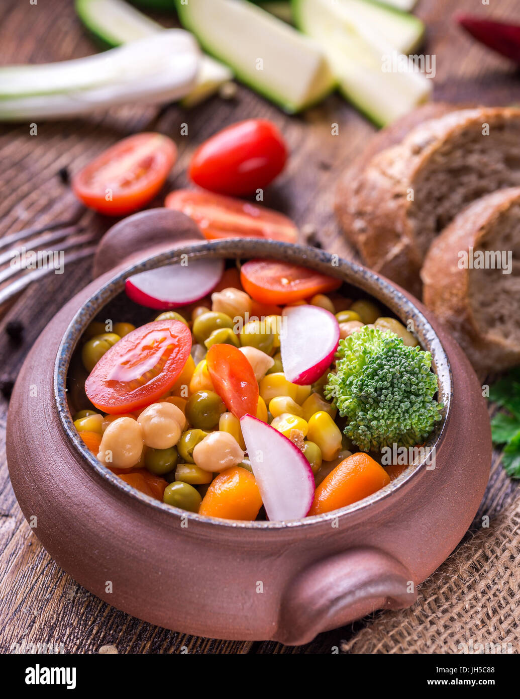 Gemüsesalat im Hause gearbeitete Schüssel mit Brot auf Holztisch. Stockfoto