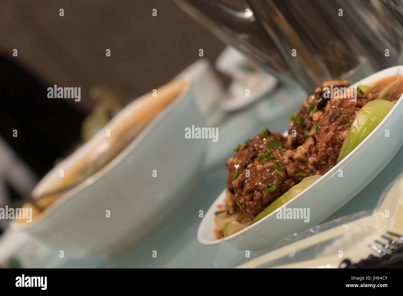 Chinesische Löwen Kopf Schweinefleischbällchen serviert an einem Tisch im Restaurant unter anderem Geschirr und Utensilien. Stockfoto