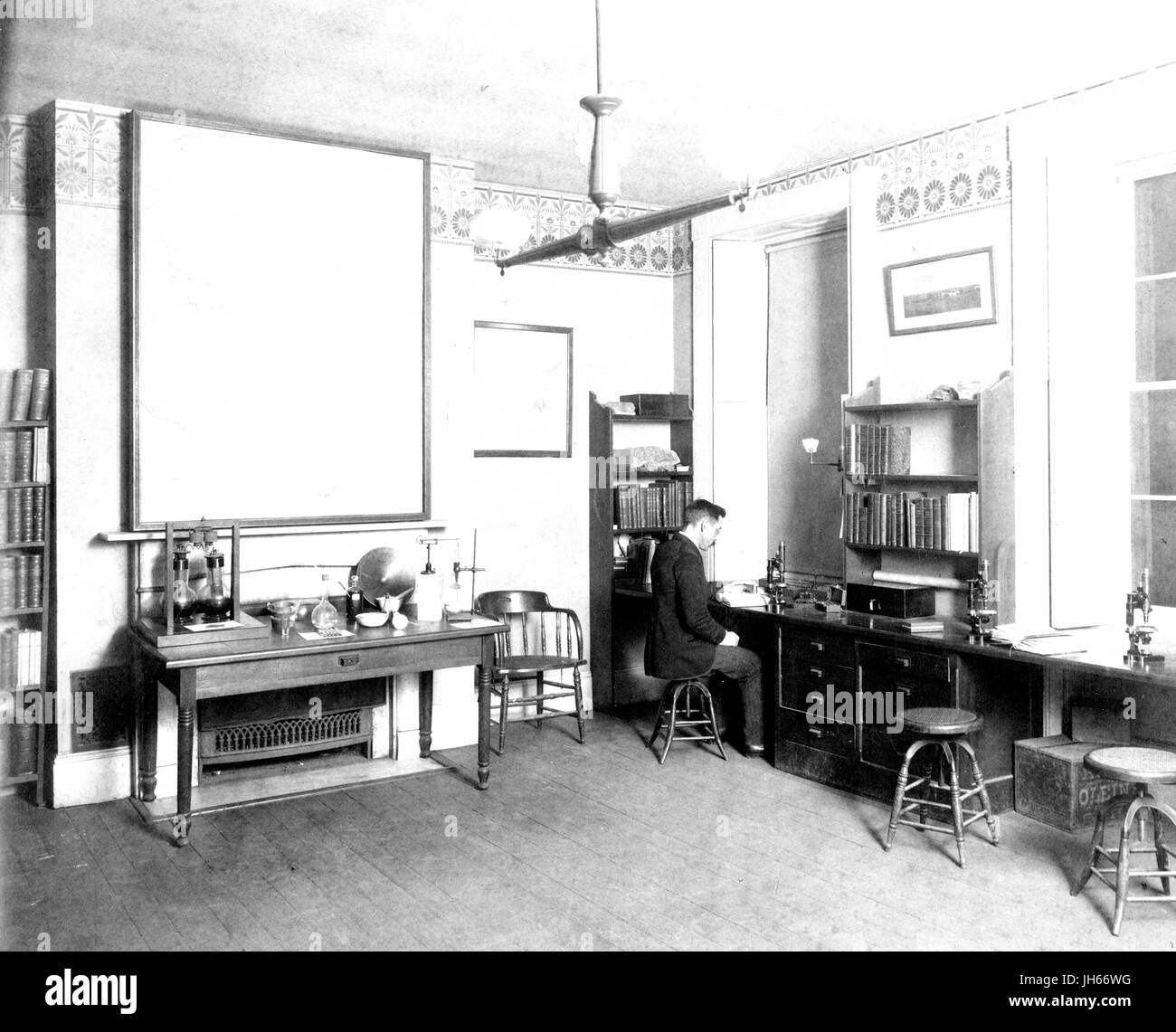 Interieur des Zimmers wurden, mit Schreibtisch, Bücherregale, Laborgeräte, und ein Mann arbeiten am Mikroskop, an der alten Campus der Johns-Hopkins-Universität in der Innenstadt von Baltimore, Maryland, 1895. Stockfoto