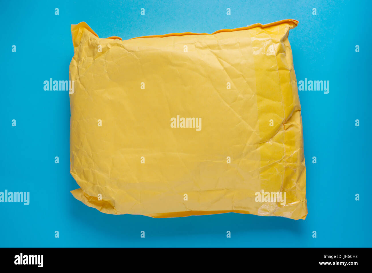 Gelbe Post Kartonverpackung auf blauem Hintergrund. Textfreiraum auf der Verpackung Stockfoto