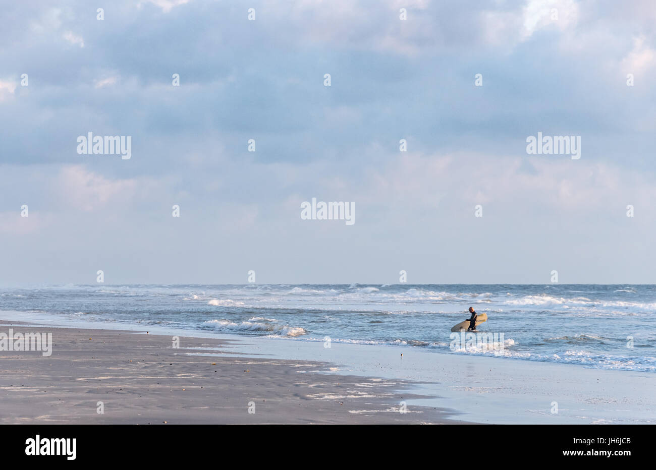 Am frühen Morgen Strandszene in Ponte Vedra Beach, Florida als senior Surfer wird das Wasser nach einer belebenden Sunrise Surf-Session beendet. Stockfoto