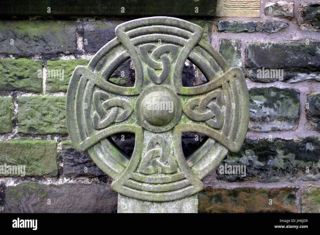 Keltisches Kreuz gegen Steinmauer Stockfoto