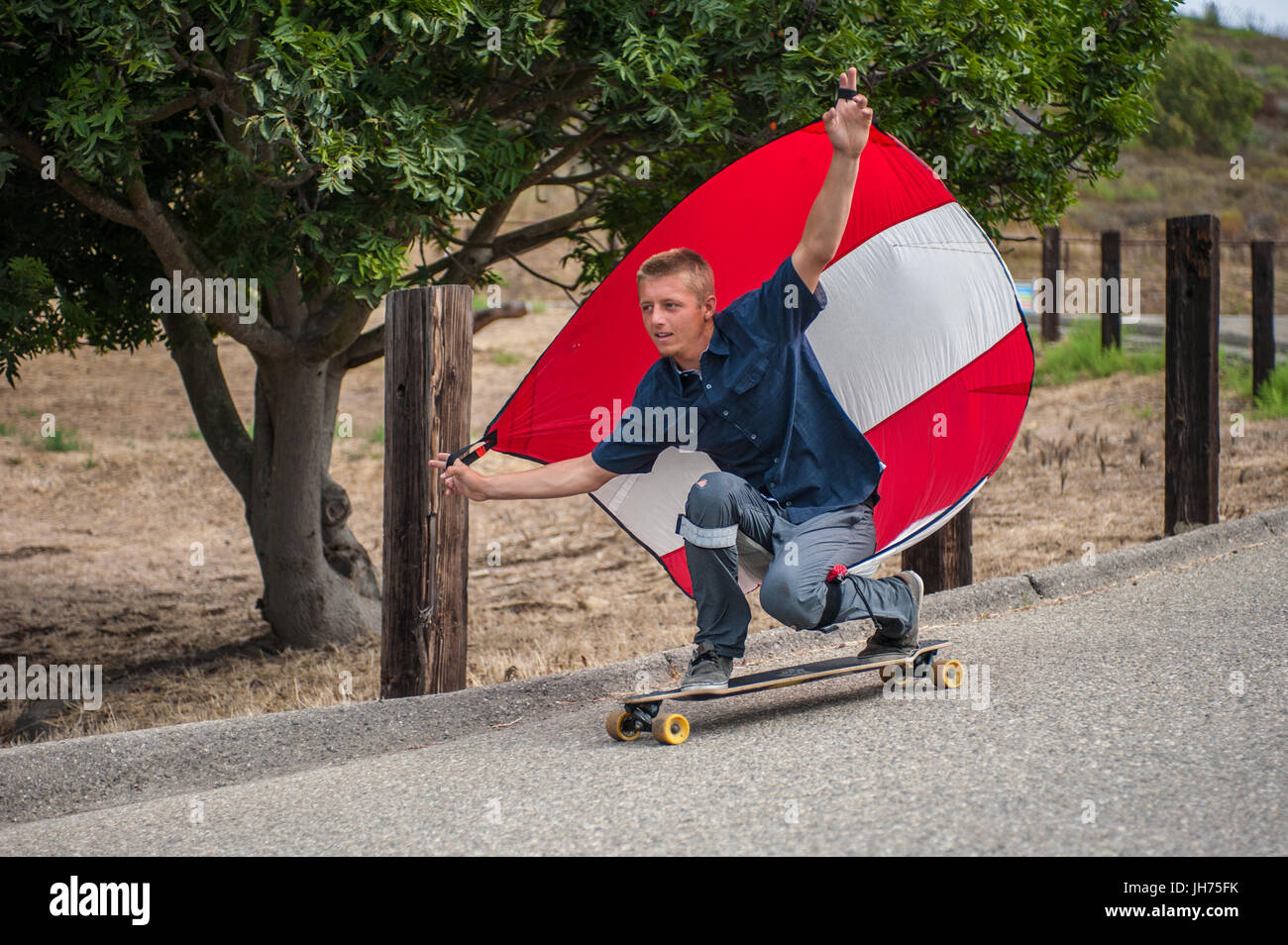 Fallschirm-downhill-Skateboarder hat Segel voll Wind, wie er duckt sich in  goofy Fuß Haltung Stockfotografie - Alamy
