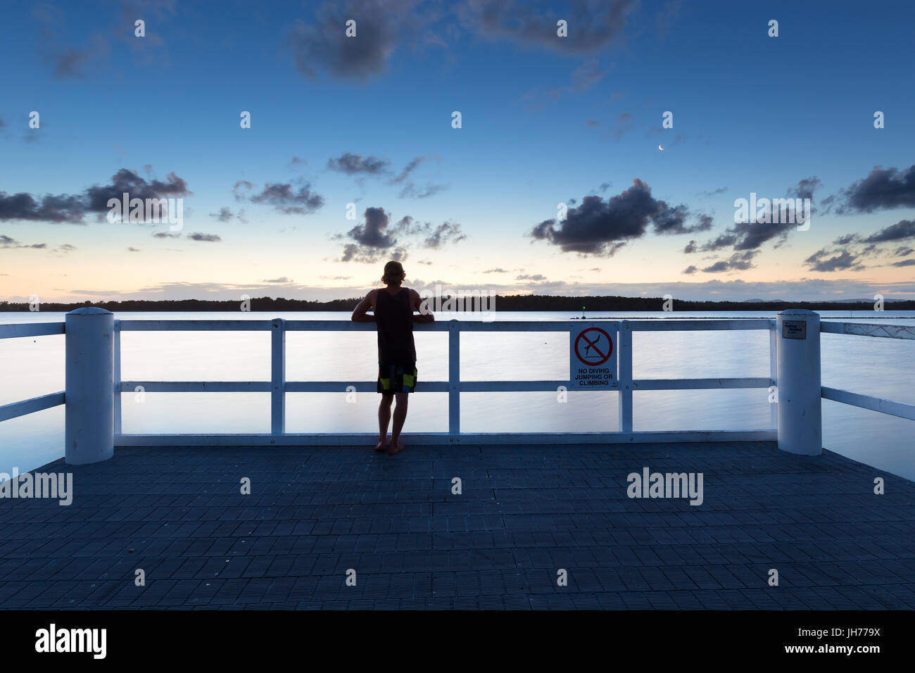 Eine Person sieht das Meer allein von einem Pier nach Einbruch der Dunkelheit in Australien. Stockfoto