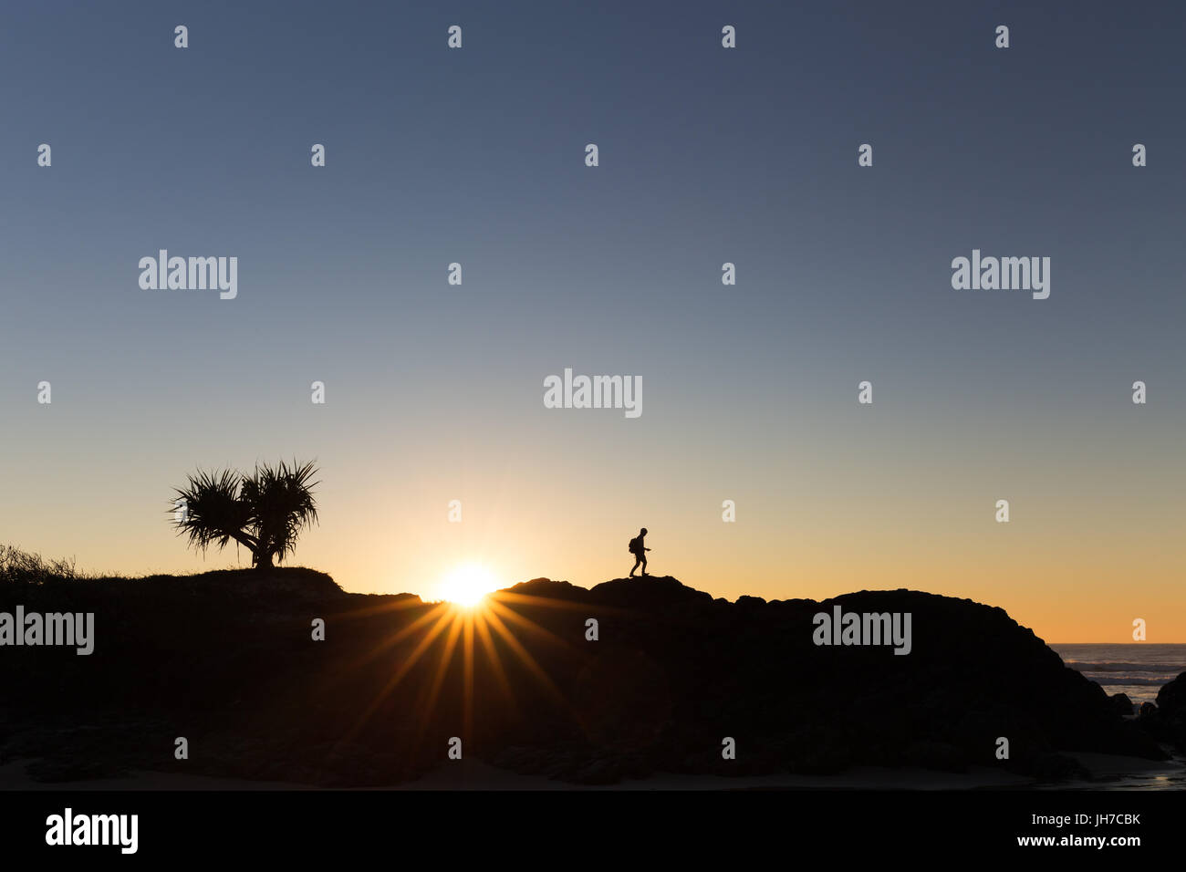Ein Wanderer zu Fuß ist in Australien von einem schönen hellen Sonnenaufgang auf einem Bergrücken Silhouette. Stockfoto