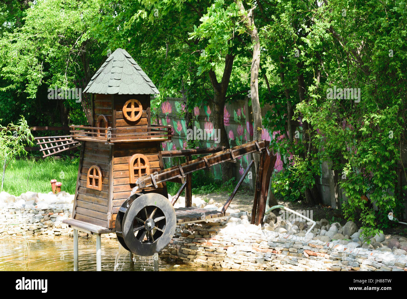 Dekorative Holz Wasser- und Windmühle befindet sich im grünen park Stockfoto