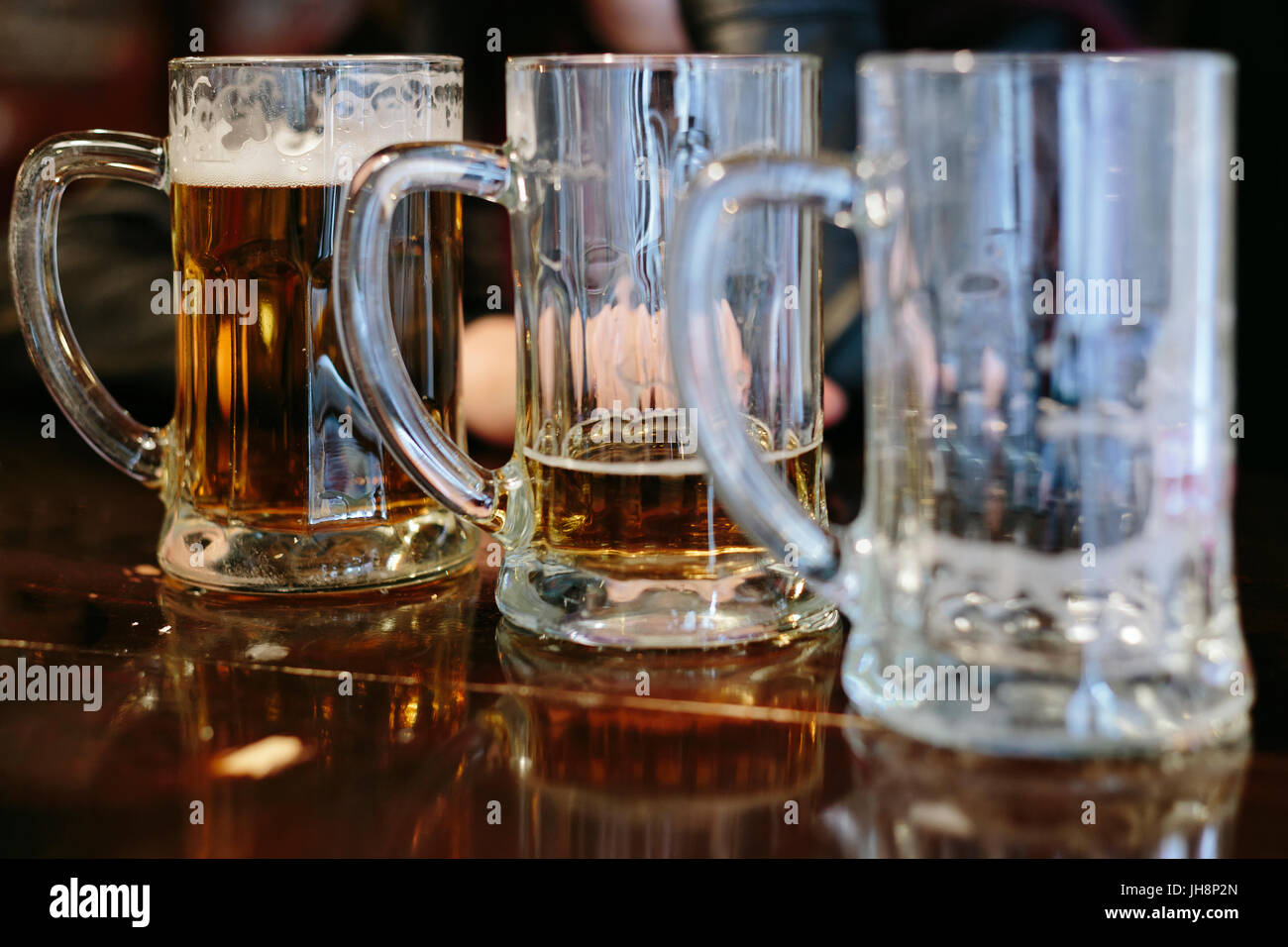 Drei Kannen mit einer unterschiedlichen Menge Bier in Ihnen Stockfoto