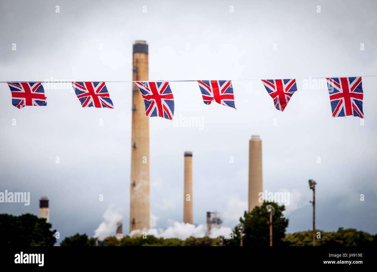 Raffinerie-Schornsteine mit Union Jack Bunting Flags im Vordergrund Stockfoto
