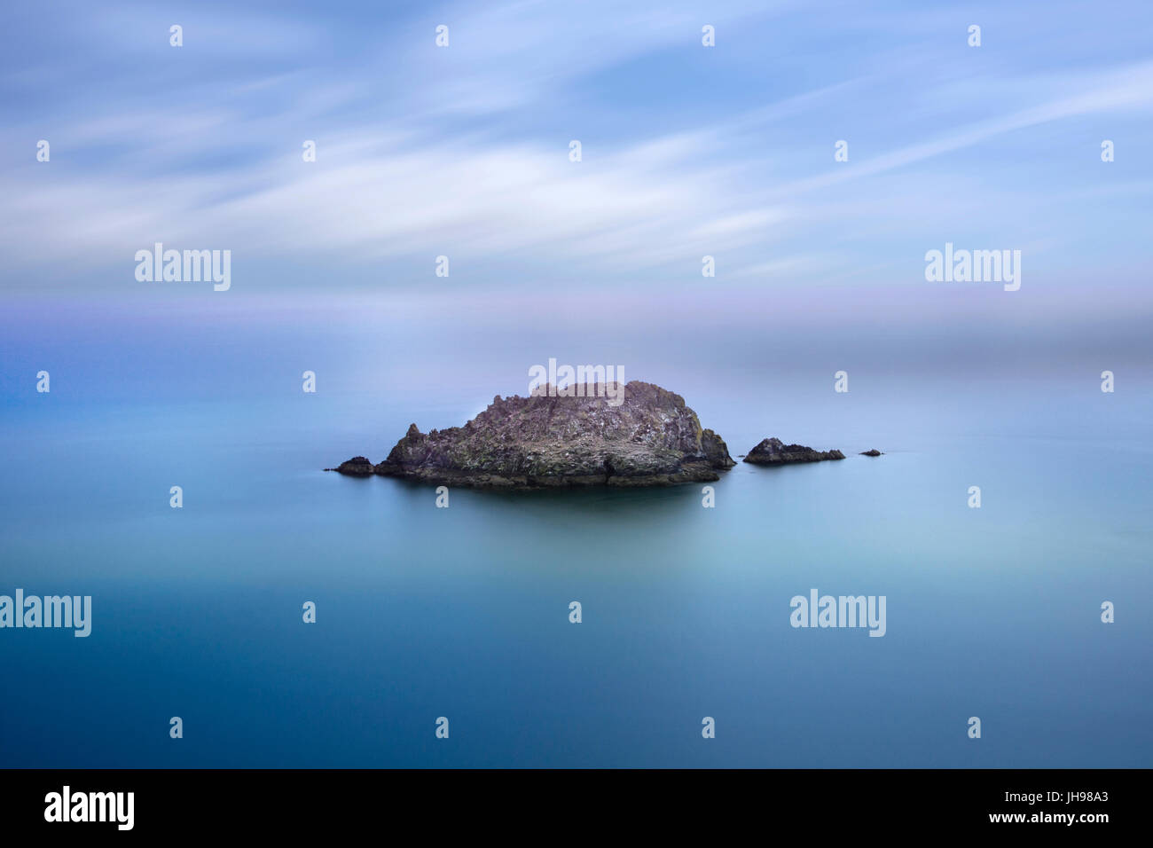 Langzeitbelichtung einer kleinen Insel, umgeben von Meer und Himmel bei Nare Kopf Roseland Cornwall Stockfoto