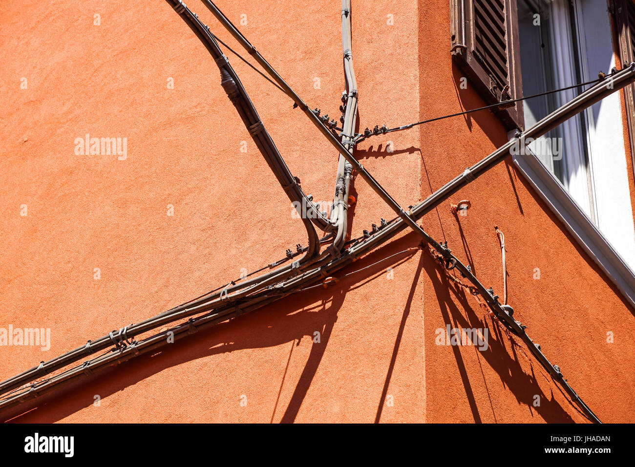 Stromkabel, Telefonkabel und metallischen Wasserleitungen vor einem alten Gebäudefassade Stockfoto