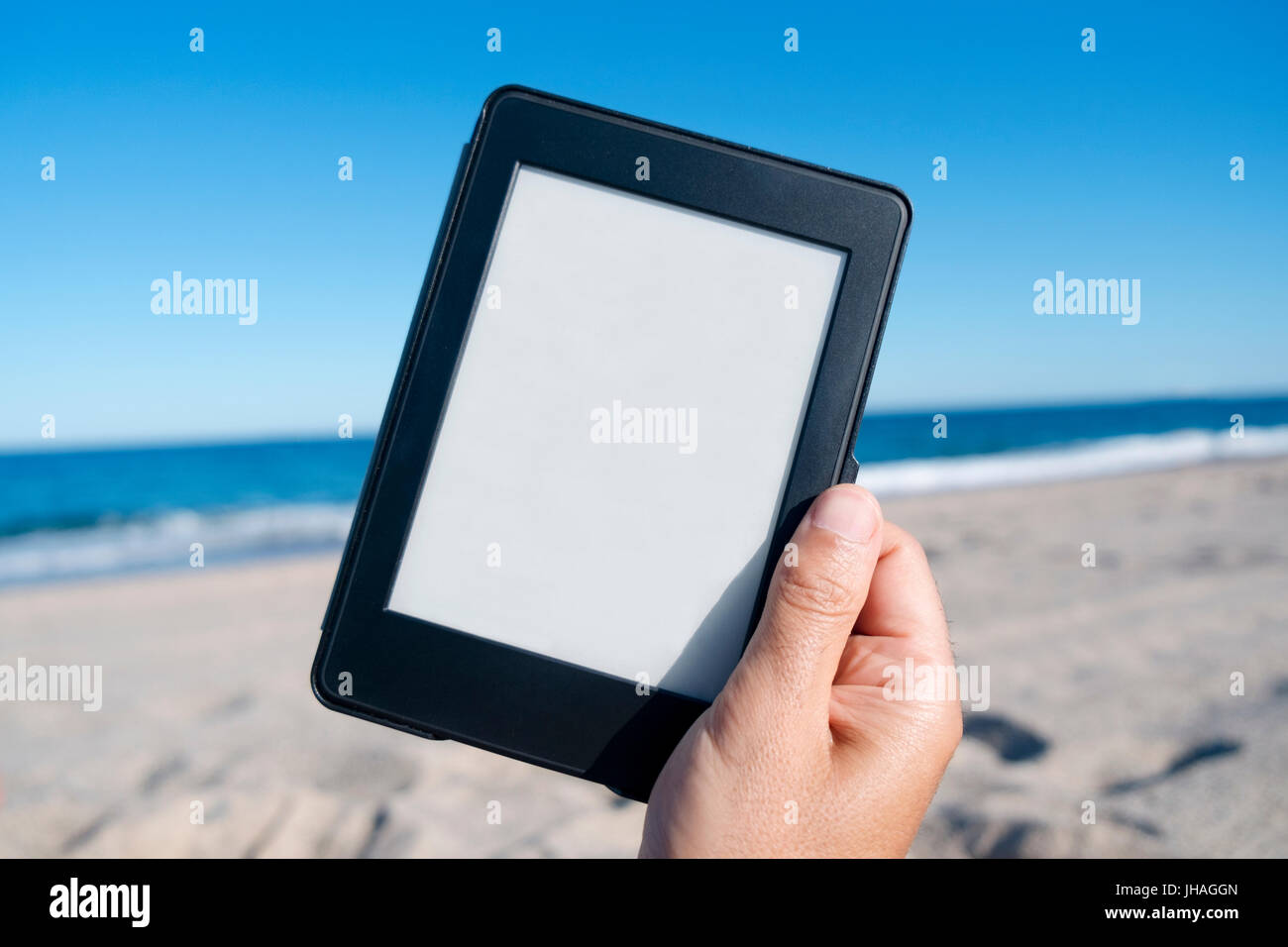 Nahaufnahme von der Hand des kaukasischen Jüngling am Strand mit einem Tablet oder e-Reader mit weißer Leerraum in seinem Bildschirm Stockfoto