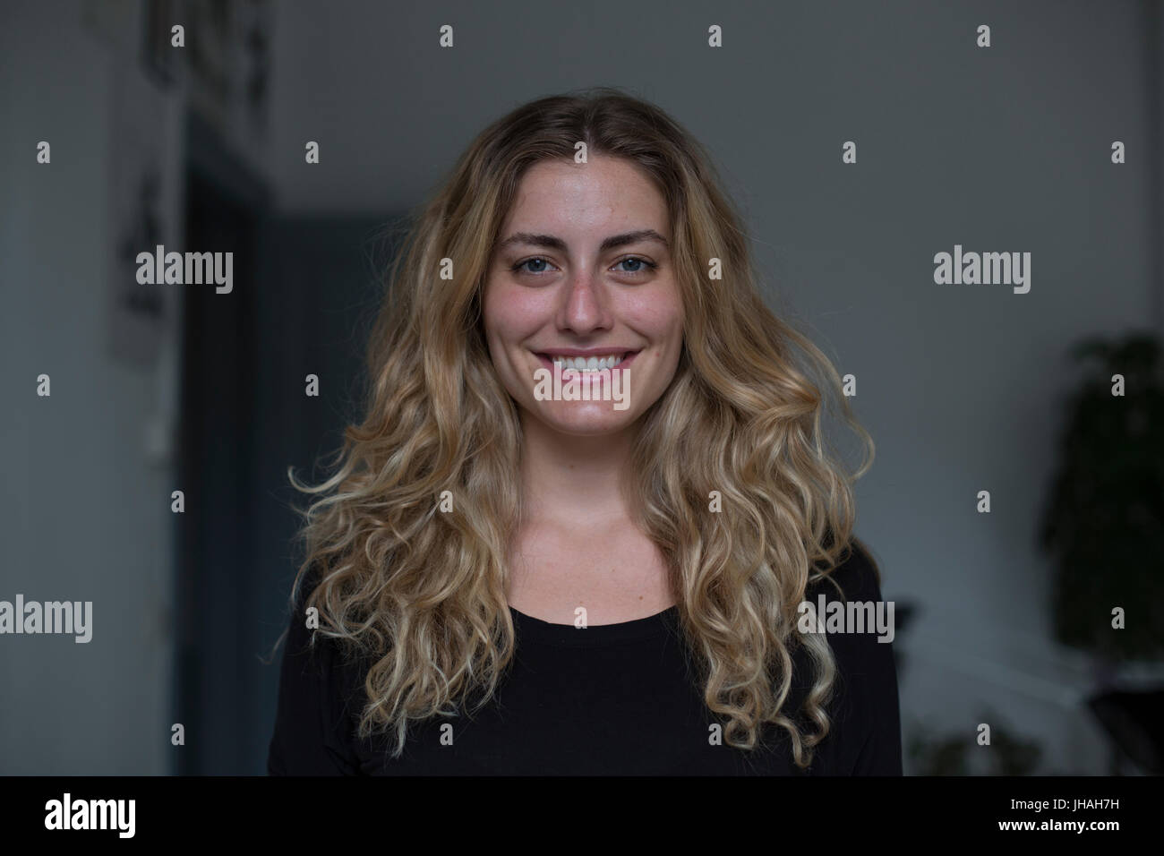 Jung, kaukasischen, blonde schöne Frau Blickkontakt mit Kamera während lächelnd, Glück in Richtung des Betrachters zum Ausdruck zu bringen. Weiche, natürliche Beleuchtung Stockfoto