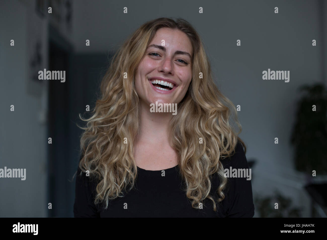 Jung, kaukasischen, blonde schöne Frau Blickkontakt mit Kamera während lächelnd, Glück in Richtung des Betrachters zum Ausdruck zu bringen. Weiche, natürliche Beleuchtung Stockfoto