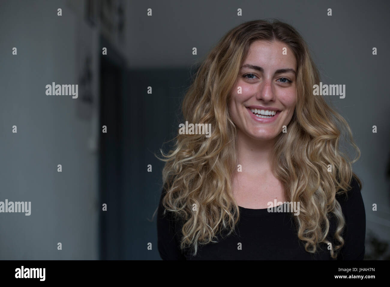 Jung, kaukasischen, blonde schöne Frau Blickkontakt mit Kamera während lächelnd, Glück in Richtung des Betrachters zum Ausdruck zu bringen. Weiche, natürliche Beleuchtung Stockfoto