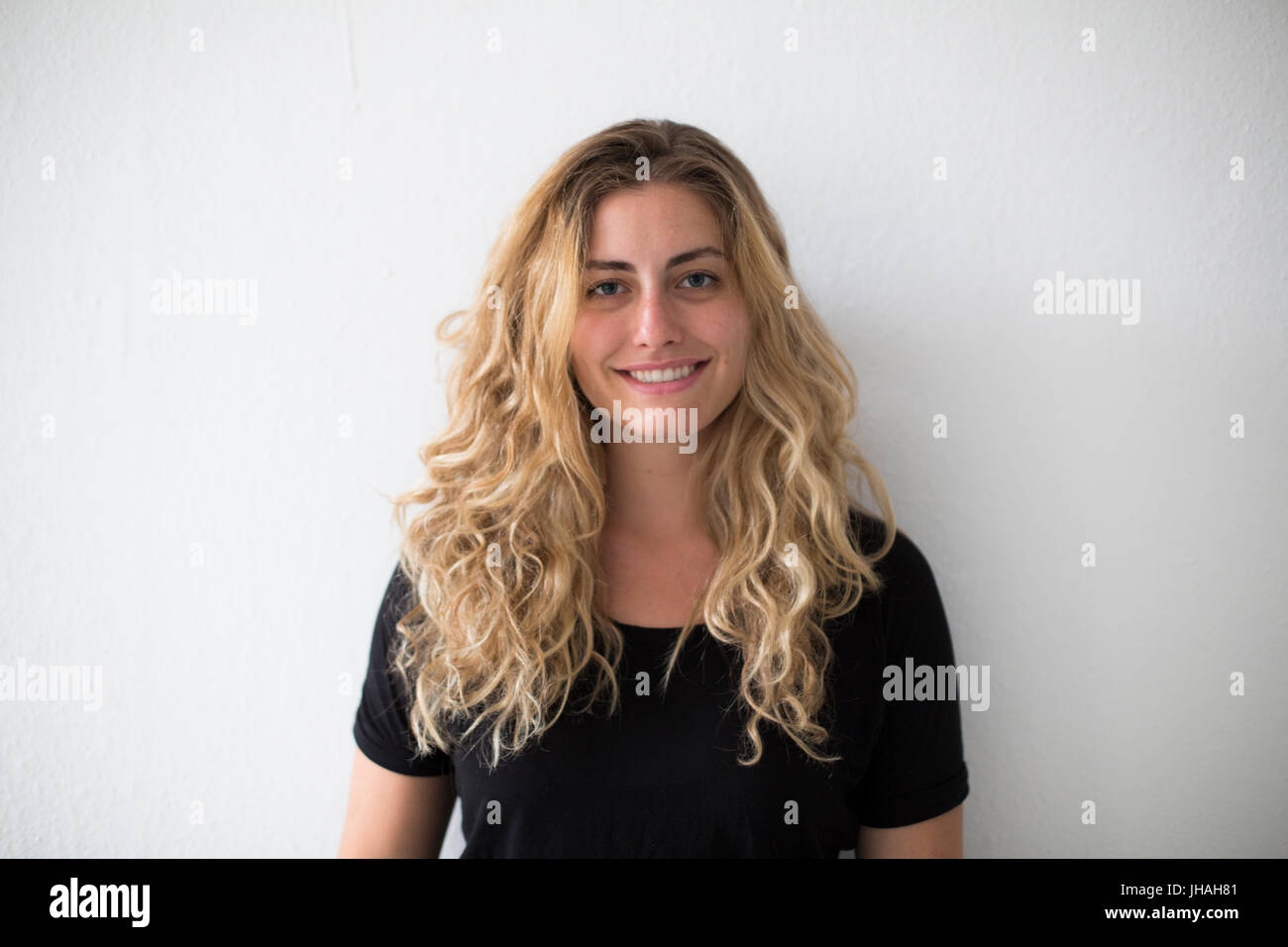 Jung, kaukasischen, blonde schöne Frau Blickkontakt mit Kamera während lächelnd, Glück in Richtung des Betrachters zum Ausdruck zu bringen. Weiche, natürliche Beleuchtung Stockfoto