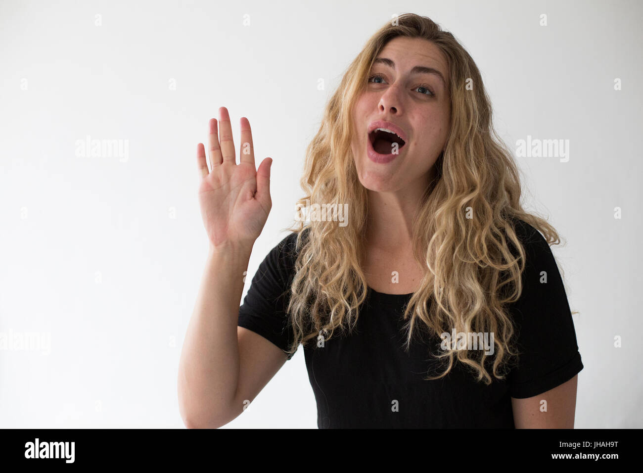 Jung, blond, schön, kaukasischen Milennial Frau zum Ausdruck bringen Aufregung und Glück während winken vor einem weißen Hintergrund. Einladend, begrüßen. Stockfoto
