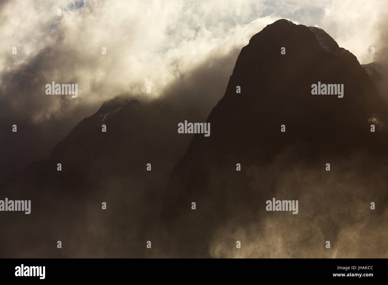 Ominöse Berggipfel in beleuchteten Wolken und Nebel eingehüllt. Stockfoto