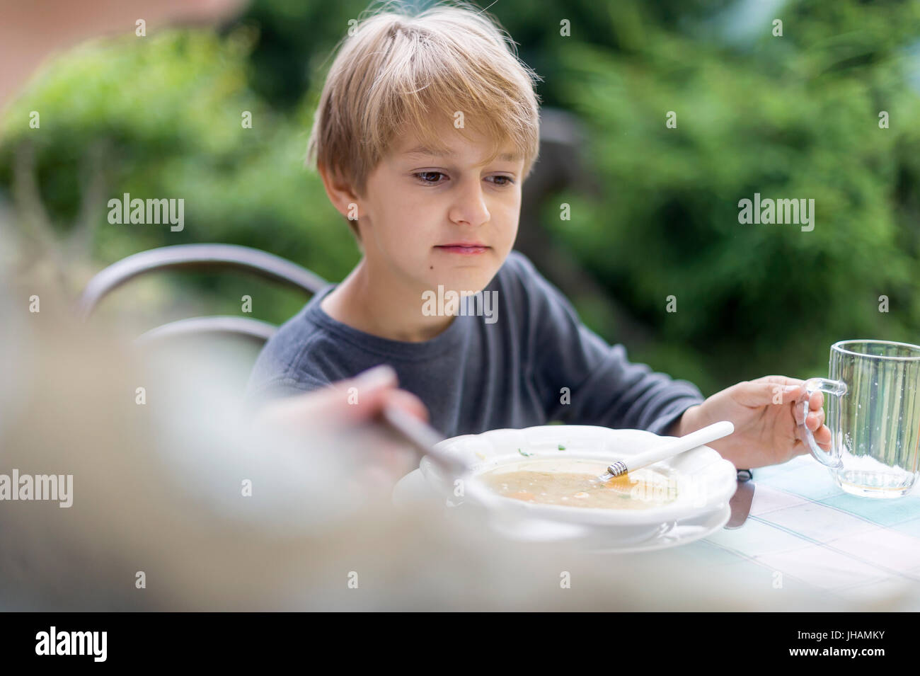 Blonder Junge essen Suppe von Outdoor-Platte Stockfoto