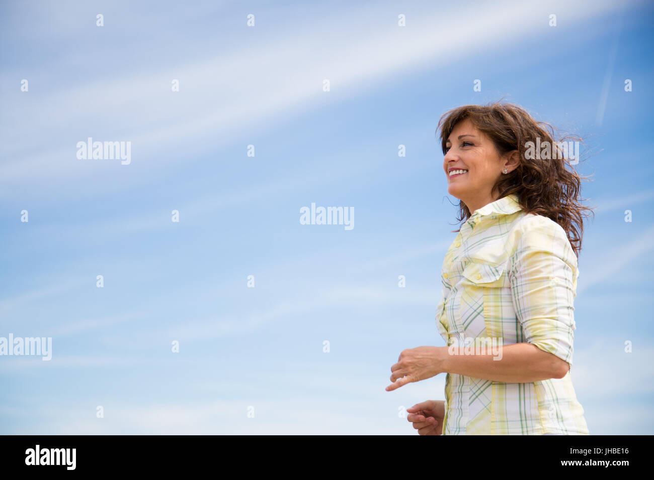 Glücklich schöne mittlere gealterte Frau zu Fuß entlang der Küste am Strand Stockfoto