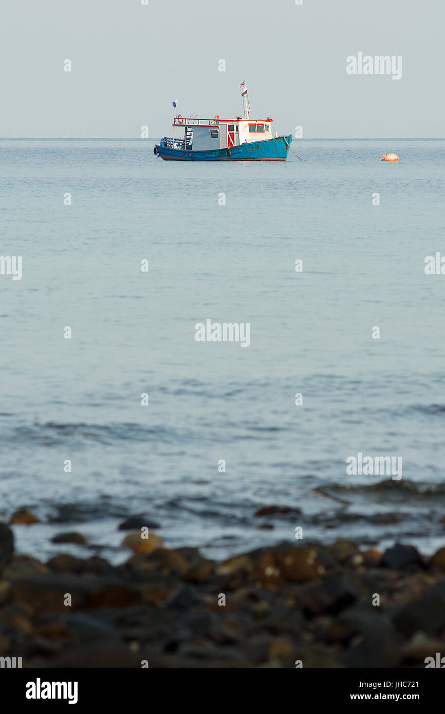 Ein Tauchen Boot schwimmt in einem ruhigen Meer, weit weg von Ufer verankert. Stockfoto