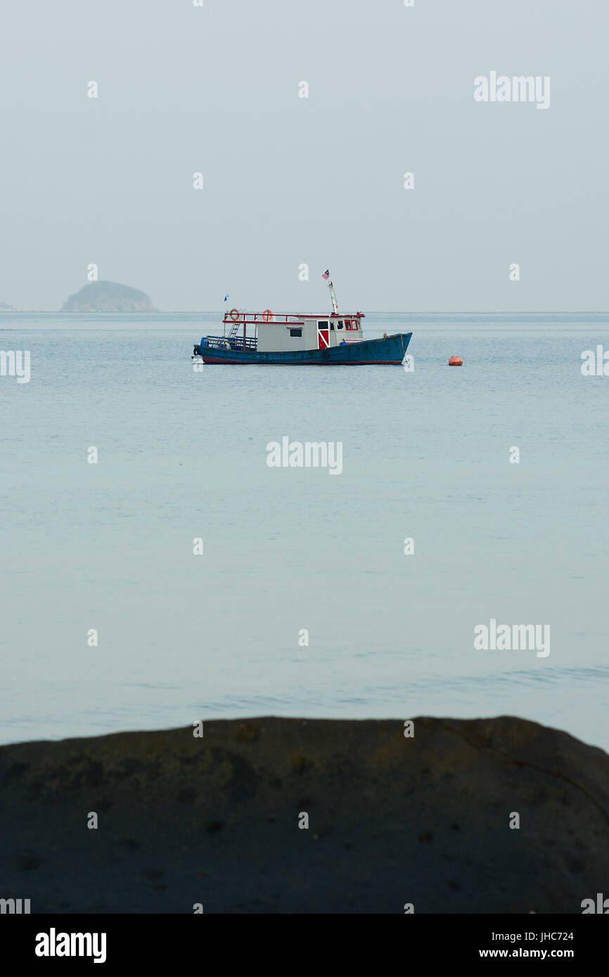 Ein Tauchen Boot schwimmt in einem ruhigen Meer, weit weg von Ufer verankert. Stockfoto