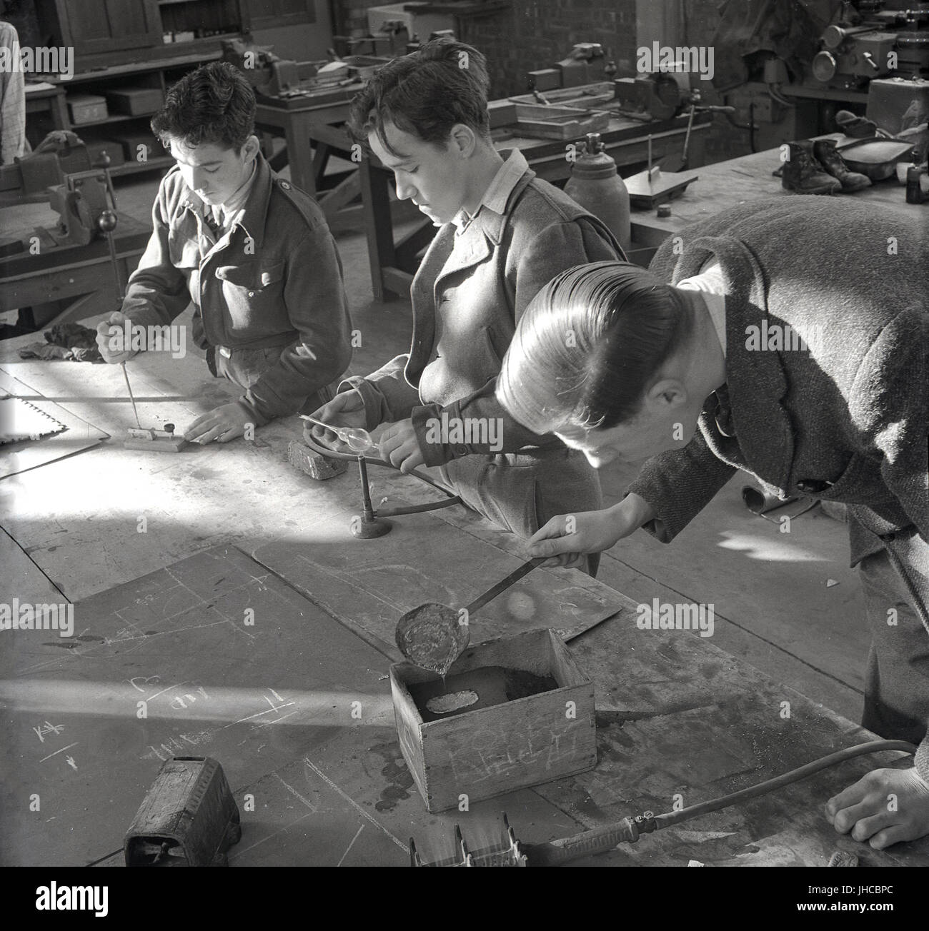 1950, historische, England, Grossbritannien, zwei männliche Schüler tragen Uniform und Lehrer tun Metall Arbeiten in einem Werkzeug Shop an der Hochschule der Technik. Stockfoto