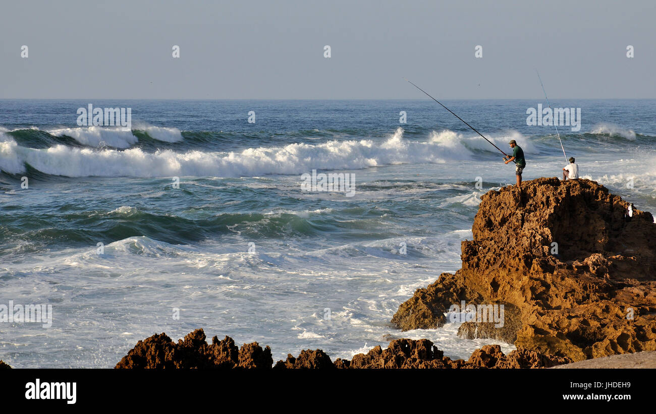 Lokale angler Fischer von zerklüfteten Felsen in einer rauen Atlantik in Oualidia Küste (El Jadida, Casablanca-Settat, Marokko) Stockfoto