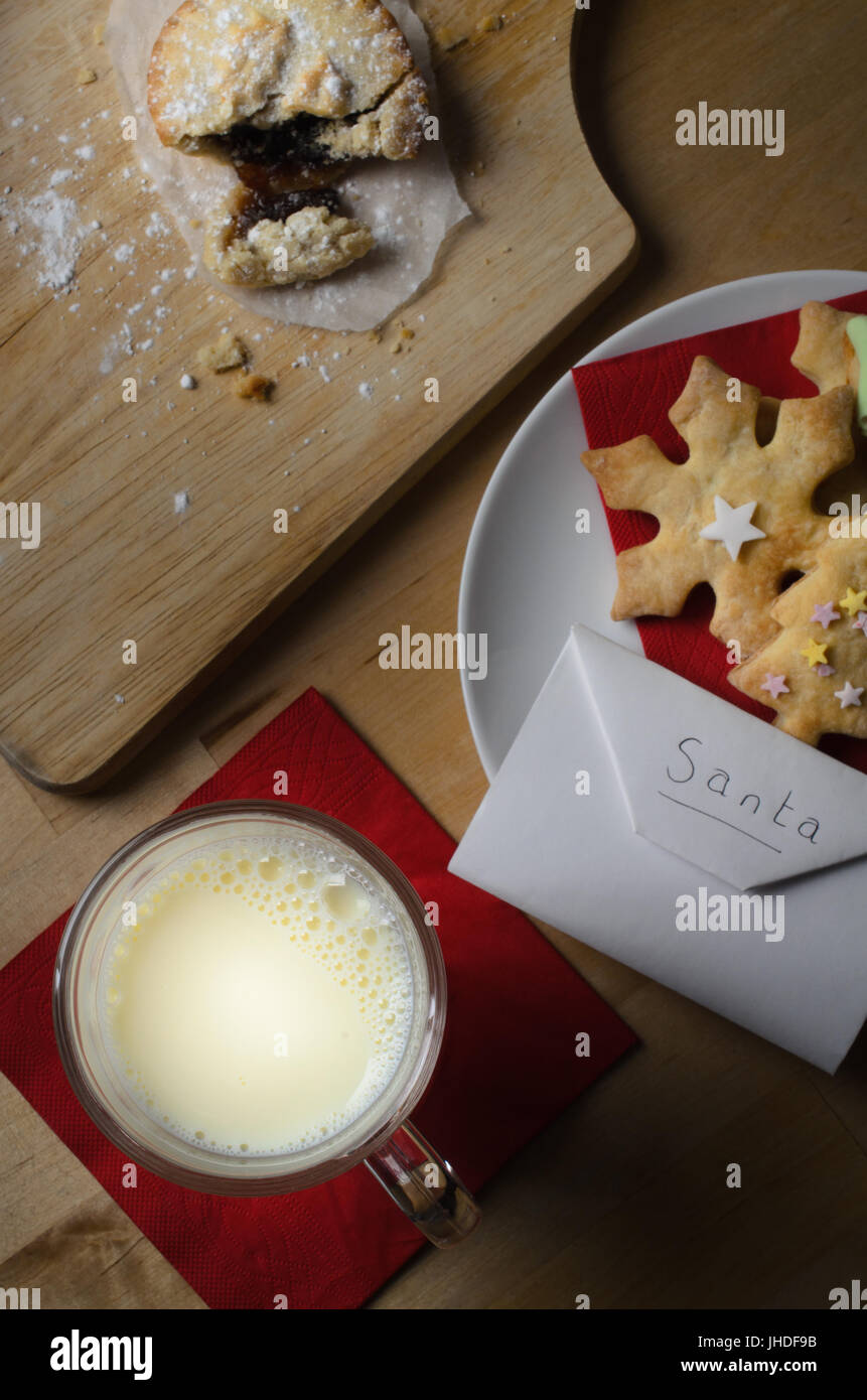 Overhead Schuss von einem Weihnachts-Nacht-Szene.  Ein Teller mit verzierten Kekse (Cookies), teilweise gegessen Mince Pie und Glas Milch mit adressierten Umschlag Stockfoto