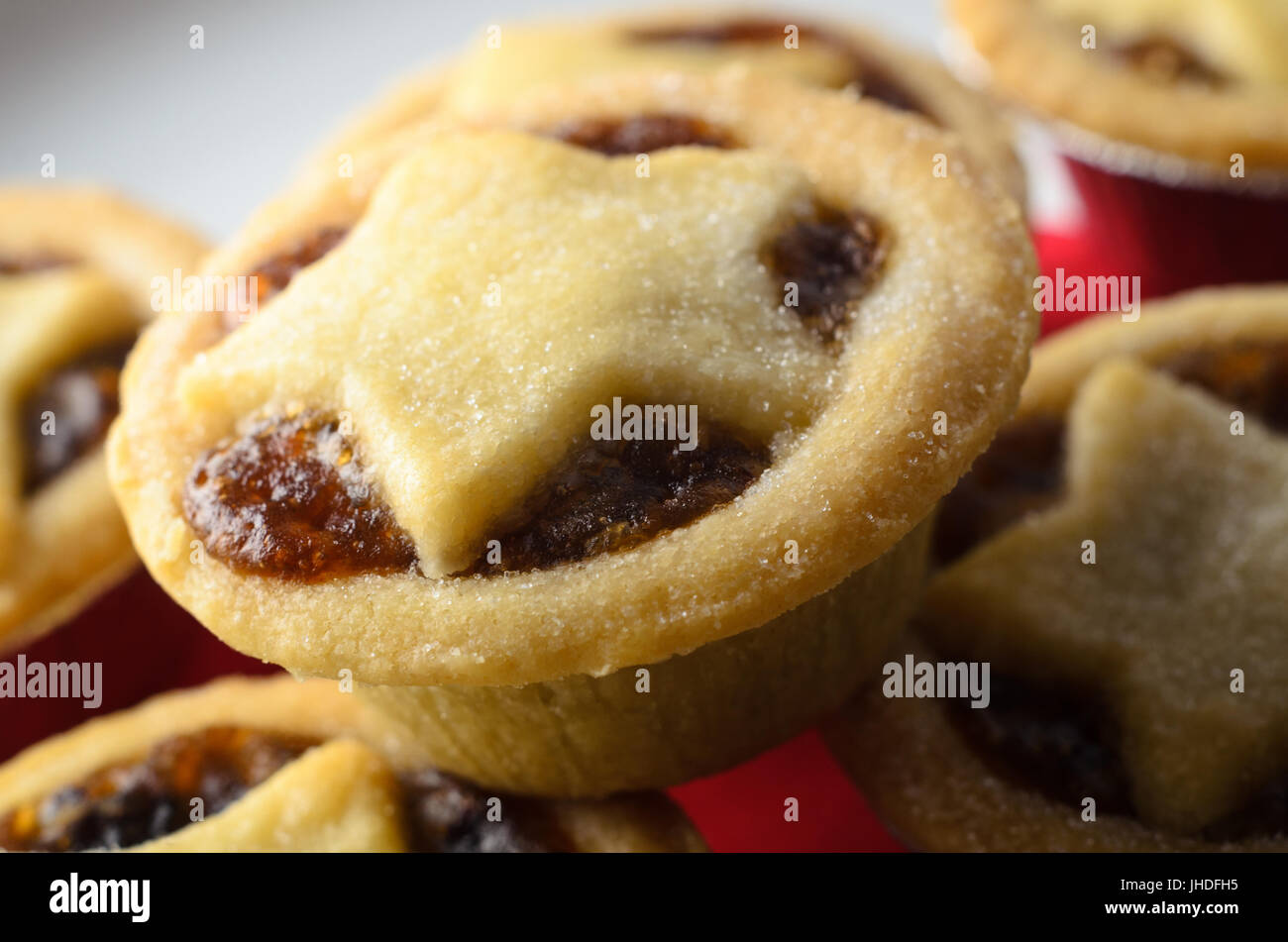 Stapel von Weihnachten Mince Pies mit Stern geformte Gebäck Tops und fruchtige Füllung ausgesetzt, auf weißen Teller mit roten Serviette. Stockfoto
