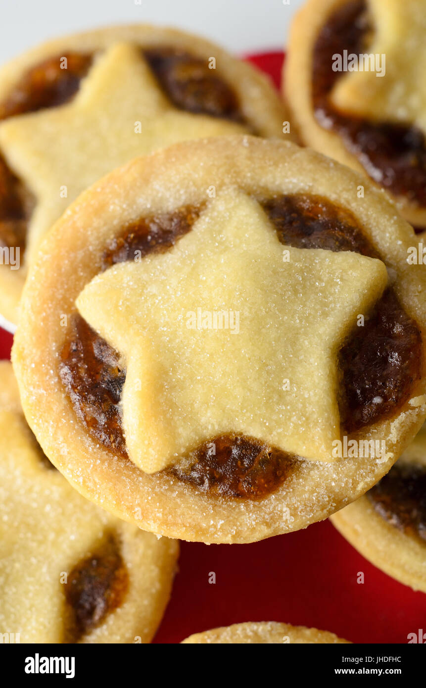 Aufwand aus einem Stapel von Weihnachten Mince Pies mit Stern geformte Gebäck Topper und Füllung ausgesetzt hautnah.  Roten Servietten und weiße Platte unten. Stockfoto