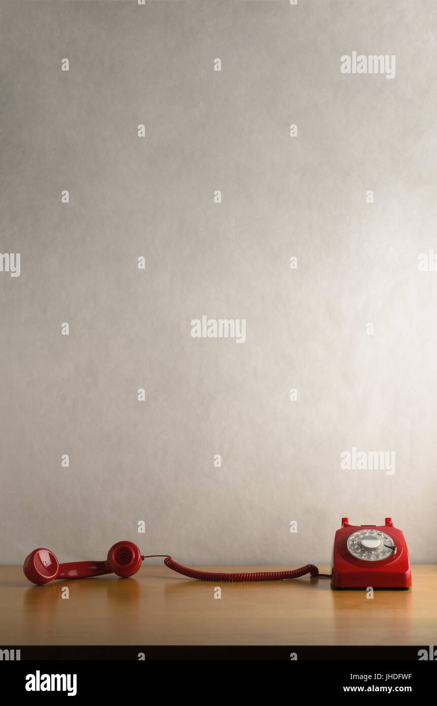Auge Ebene Schuss retro rot DFÜ-Telefon auf einem leichten Holzfurnier Schreibtisch oder Tisch mit Mobilteil vom Haken genommen und gezogene quer dazu.  Weg vom weiß Stockfoto