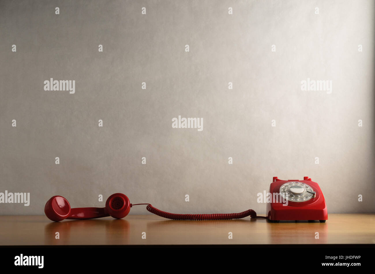 Auge Ebene Schuss retro rot DFÜ-Telefon auf einem leichten Holzfurnier Schreibtisch oder Tisch mit Mobilteil vom Haken genommen und gezogene quer dazu.  Weg vom weiß Stockfoto