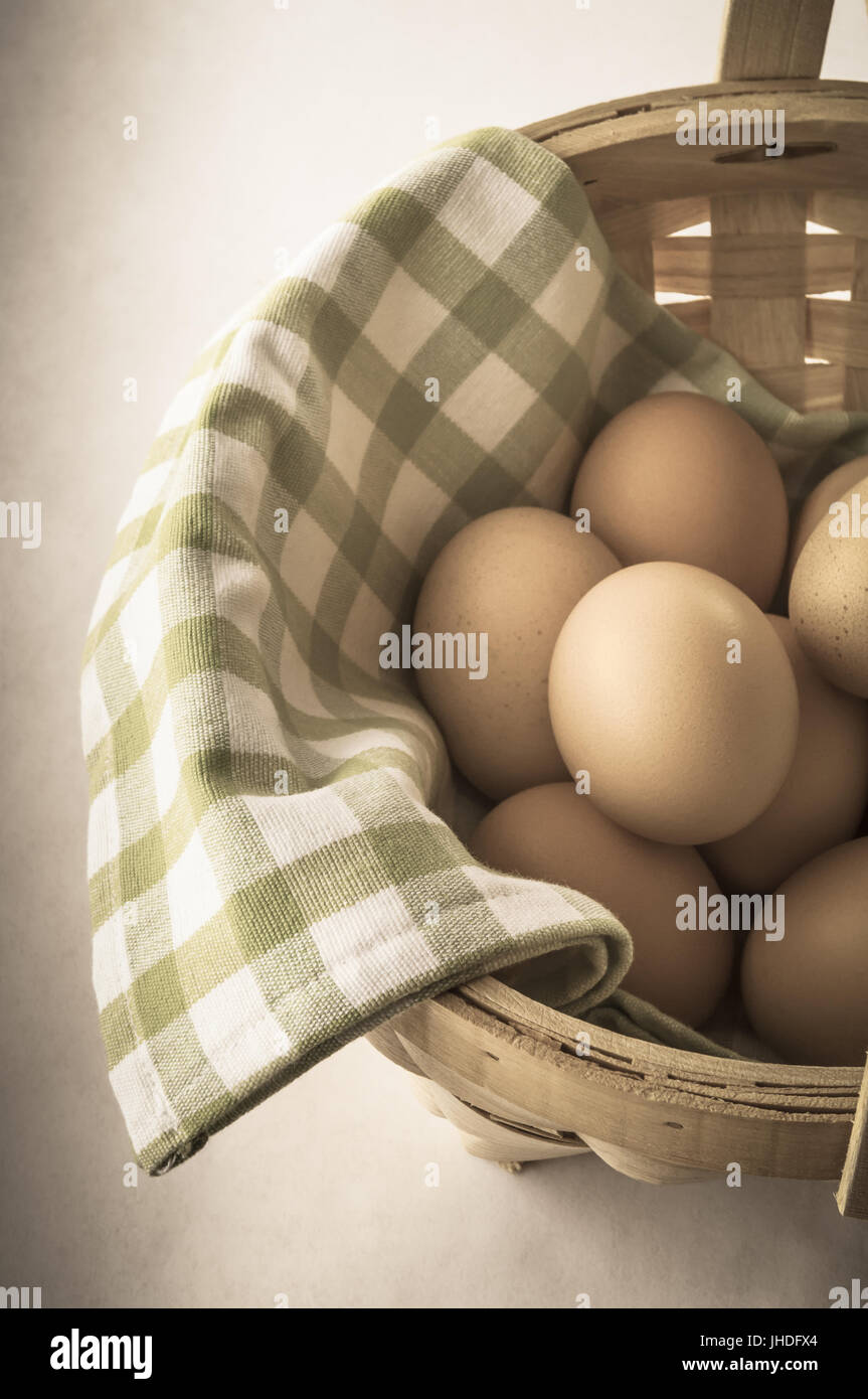 Einen Korb mit gesammelten Eiern mit grün-weißen aufgegebenes karierte Baumwollstoff gefüttert.  Teilweise entsättigt und vignettierten für retro, Vintage-Effekt. Abgewinkelt Stockfoto