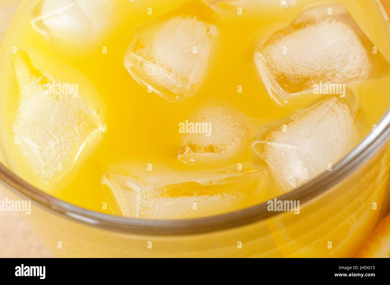 Ein Glas Orangensaft mit Eiswürfeln gefüllt. Nahaufnahme, schräg von oben. Stockfoto