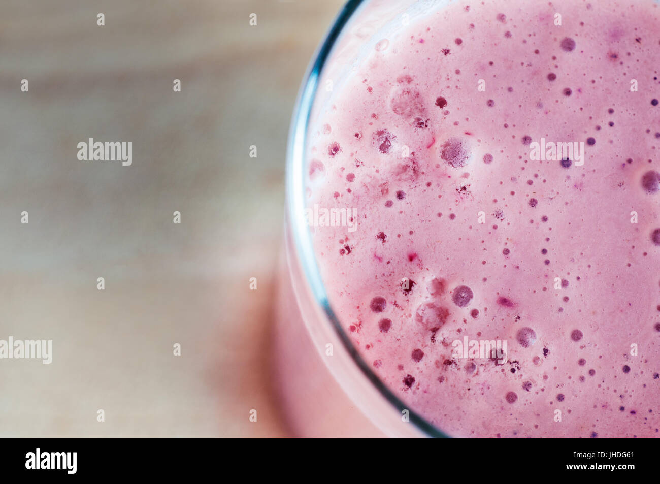 Abgewinkelt, overhead schließen sich eine schaumige rosa Smoothie aus Sommer Obst und Soja Milch hergestellt. Stehend auf Holz die Weichzeichner Textfreiraum, bietet die Stockfoto