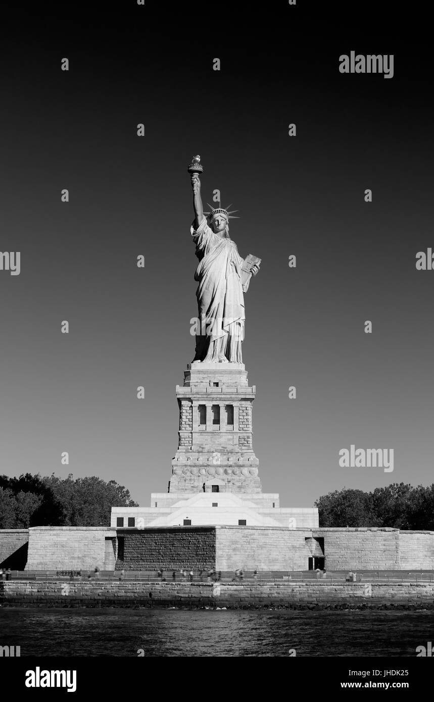 Freiheitsstatue mit Sockel und Liberty Island an einem sonnigen Tag, New York in schwarz / weiß Stockfoto