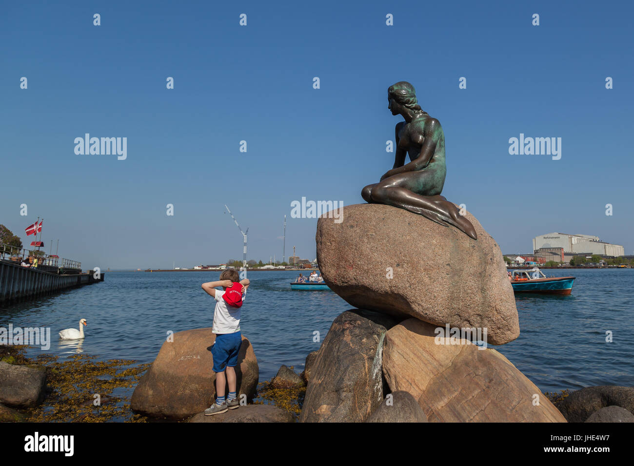 Ein Junge auf die Statue der kleinen Meerjungfrau in Kopenhagen, Dänemark. Stockfoto