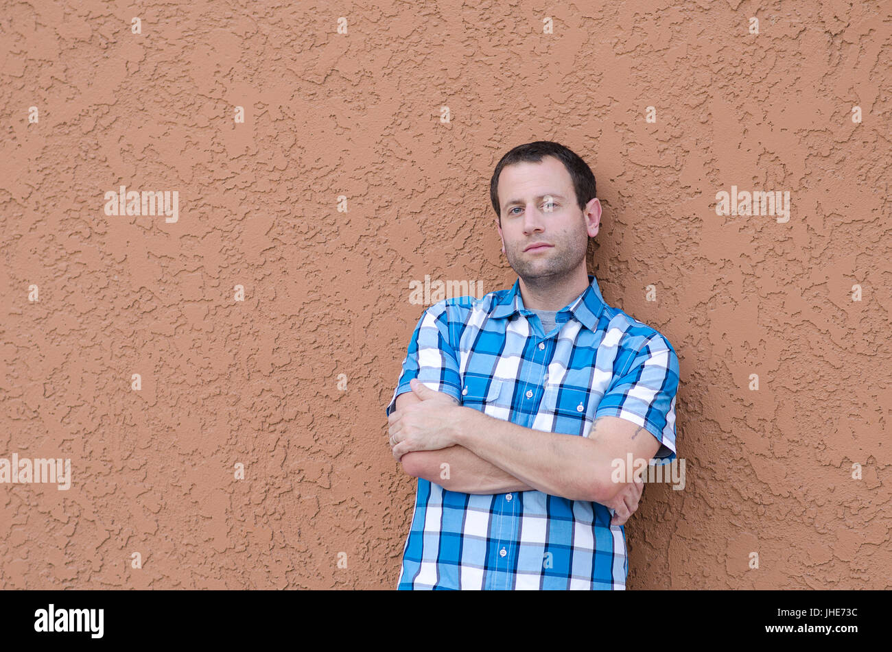 Man gegen eine Wand mit seinen Armen lehnte sich gekreuzt. Stockfoto