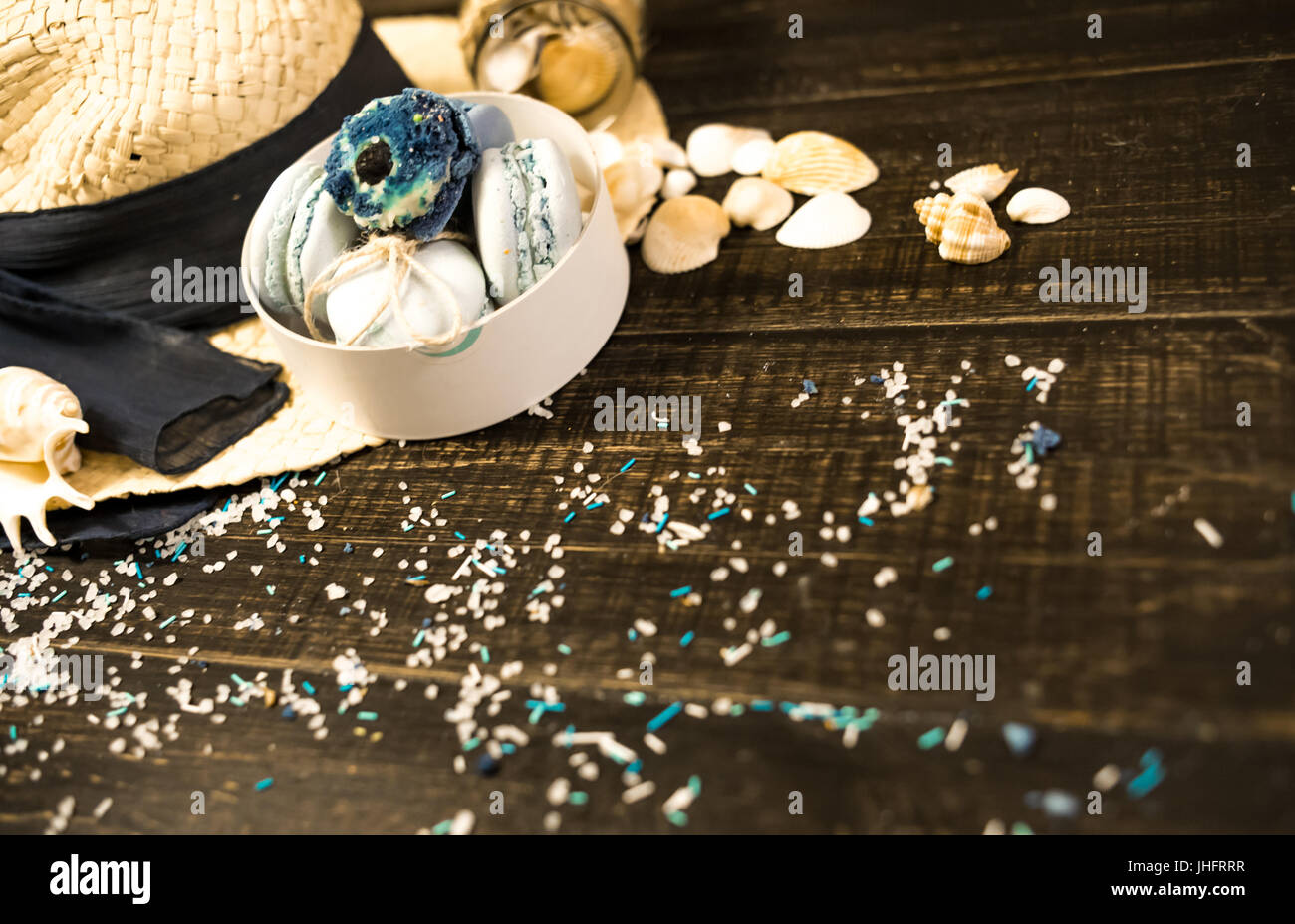 Strohhut mit blauen Makronen und Meersalz mit Muscheln auf Holz Hintergrund Stockfoto