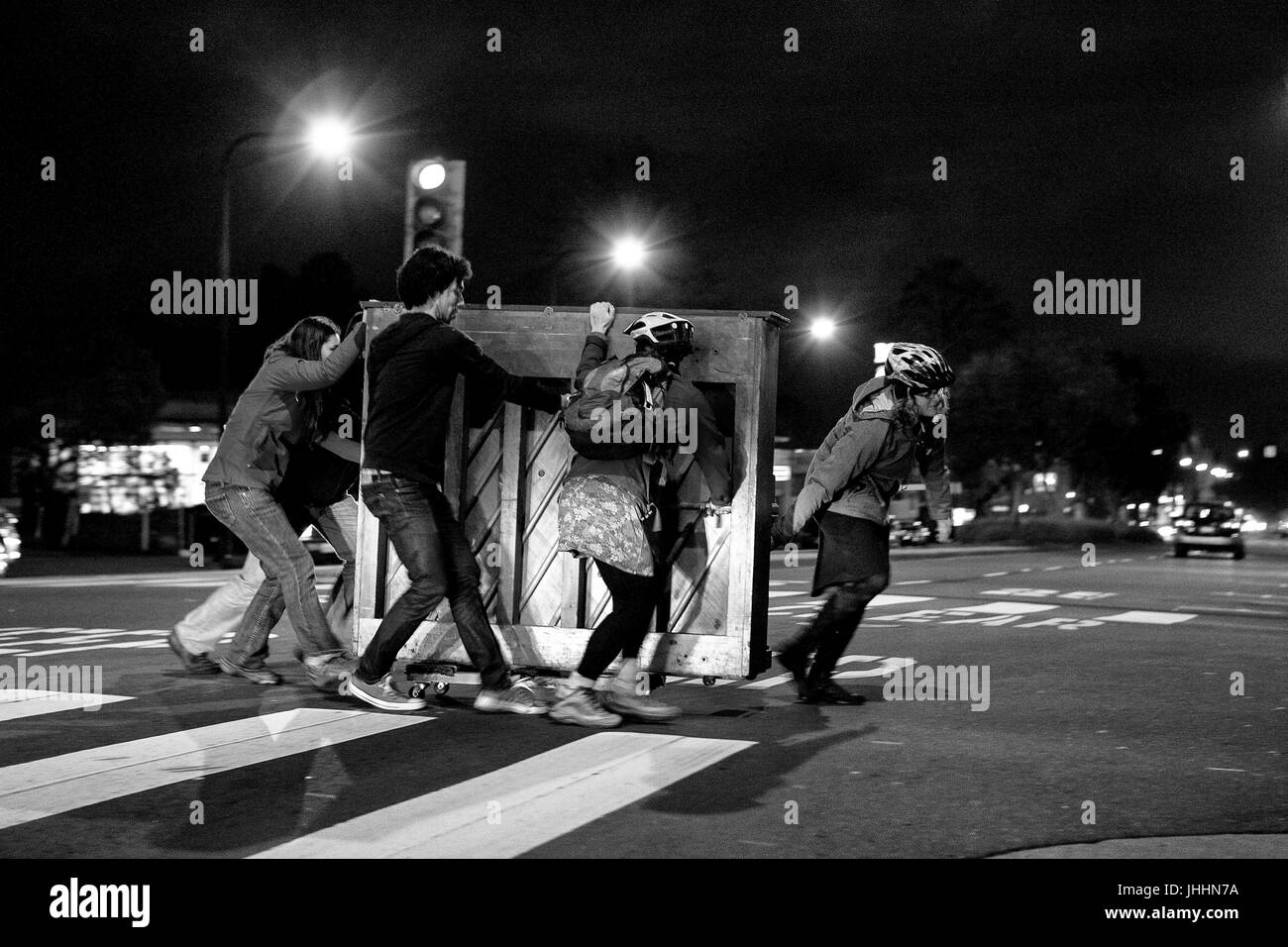 Menschen arbeiten zusammen, um ein Klavier in einer Straße zu schieben. Stockfoto