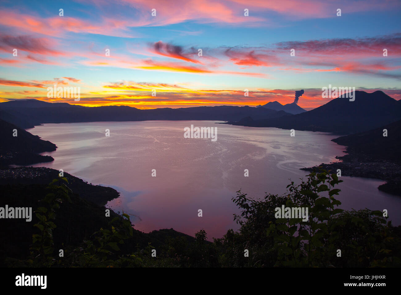 Sonnenaufgang über dem See Atitlan mit Volcan Fuego durchbrechenden im Hintergrund Stockfoto Sonnenaufgang über dem See Atitlan mit Volcan Fuego durchbrechenden im Hintergrund Stockfoto